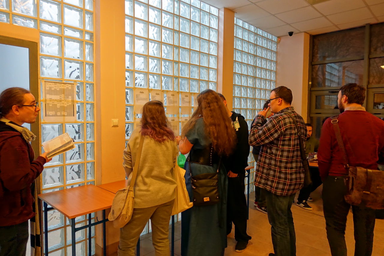 People standing in front of the glass wall. A few sheets of paper is sticked to the wall.
