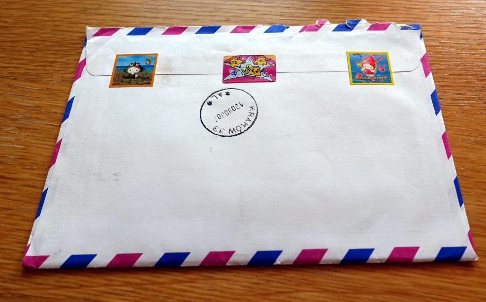 Back of an envelope with three stickers keeping it closed.