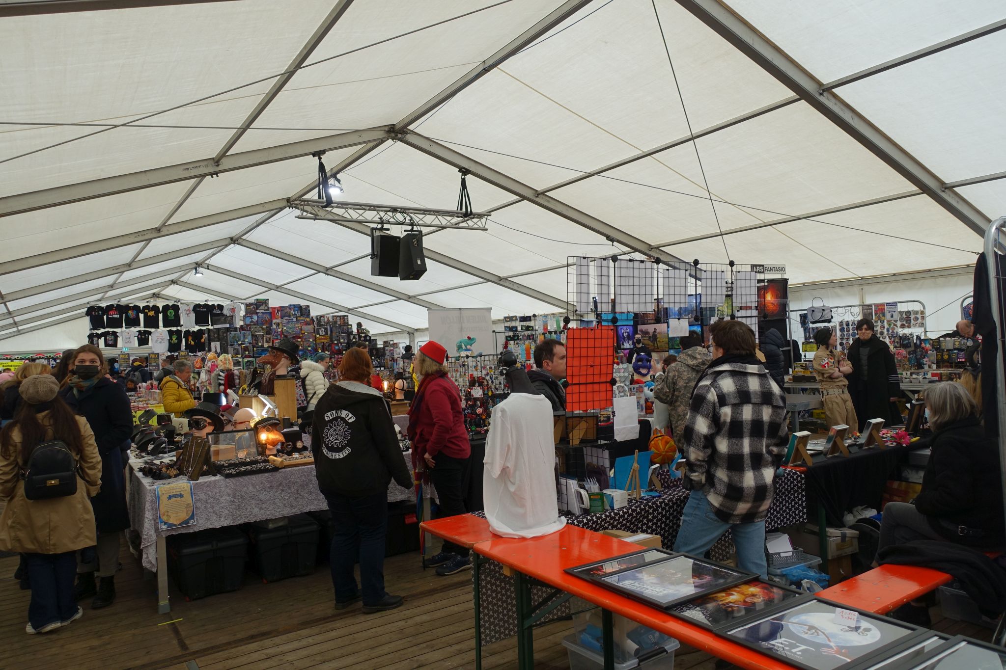 Interior of the tent with many dealers tables and some people.