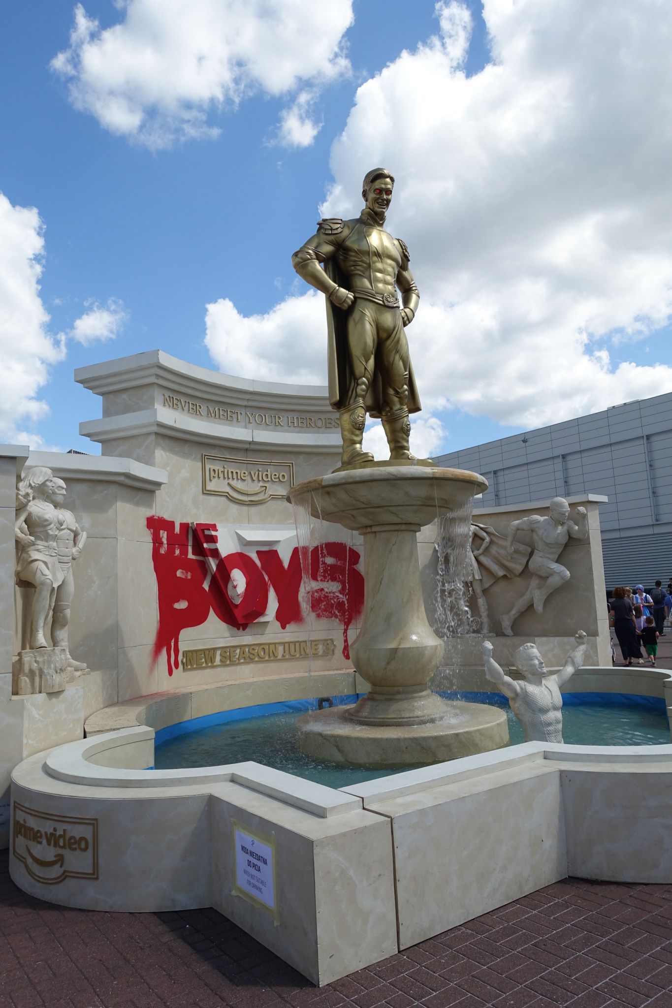 Fountain with golden man figure. On the back wall of the fountain one can see big inscription in red letters: 'The Boys'.
