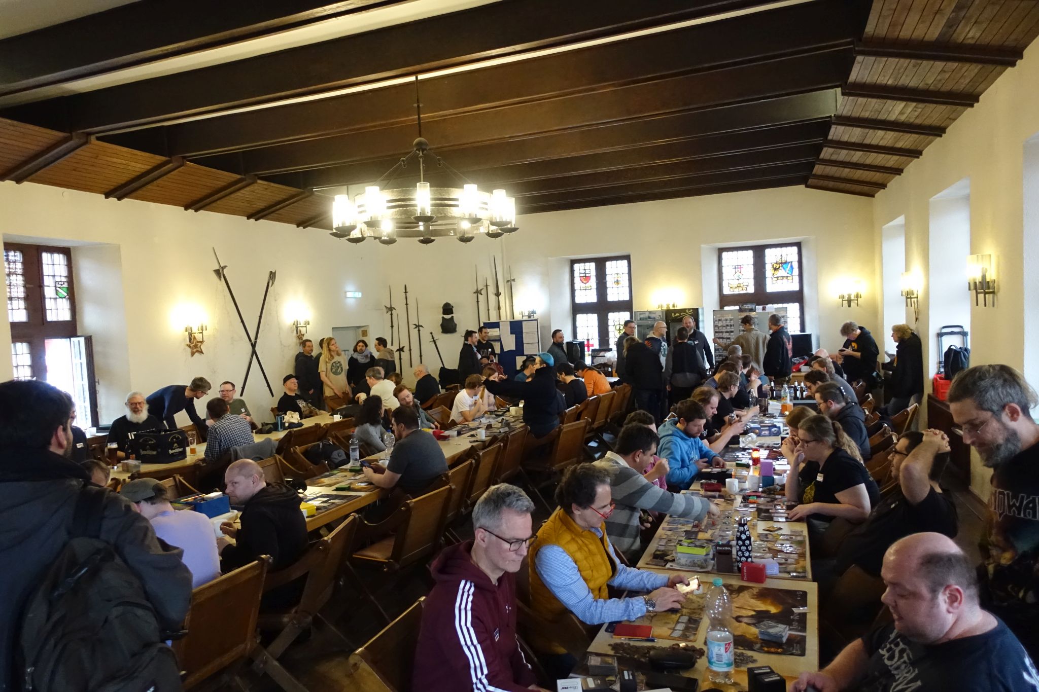 A hall full of long tables. There are games on the tables and people play them.