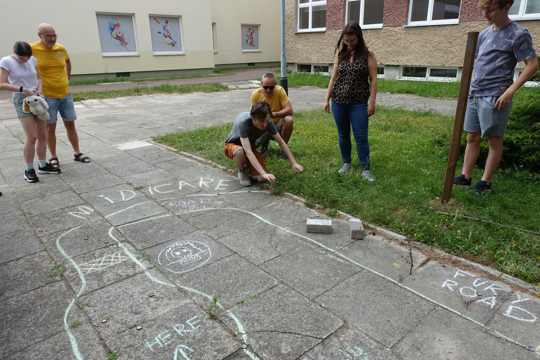 Picture shows a route drawn with chalk on the pavement. There are a four people standing, and two coruching next to it. 
